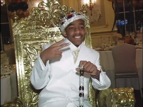 A boy dressed as a king on a throne in a super sweet 16 reality show